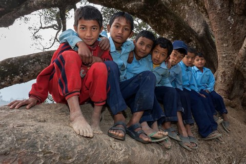 Nepalese students wearing school uniforms sitting on a tree