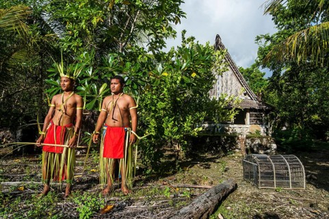 Two traditionally dressed men standing in front of stone money