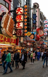 Many pedestrians crowded into pedestrian zone with lots of advertising signs for restaurants and shopping centers