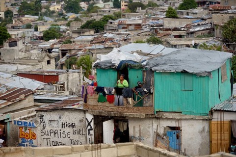 Woman on the balcony of her green-painted shack
