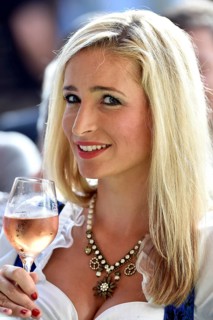 Young woman wearing a dirndl dress holding a wine glass