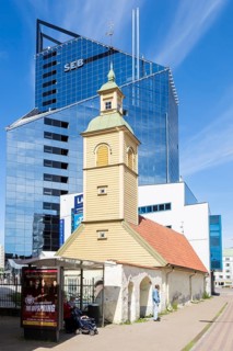 Wooden church in front of modern building of SEB bank in the financial and business district
