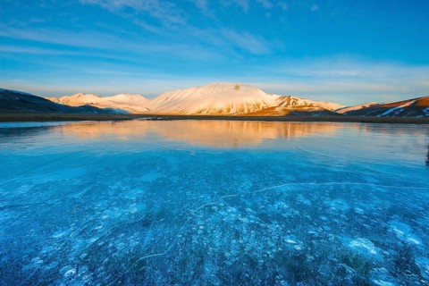 Monte Vettore in the evening light with a frozen puddle with air bubbles