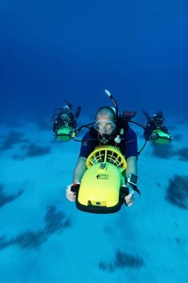 Divers with diver propulsion vehicles exploring a coral reef