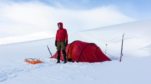 Ski tourer with tent in the snow