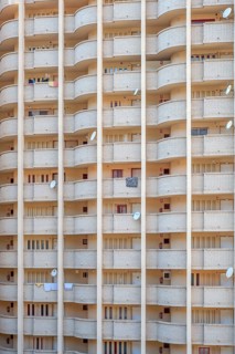 Facade of a skyscraper with satellite dishes on balconies