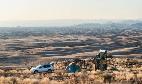 SUV next to tent and small hut
