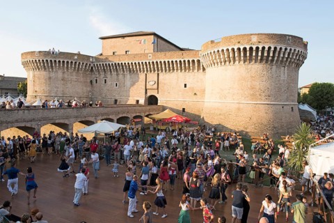 People dancing in the festival grounds in front of Fortress Rocca Roveresca