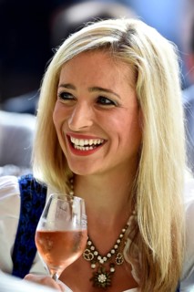Young woman wearing a dirndl dress holding a wine glass