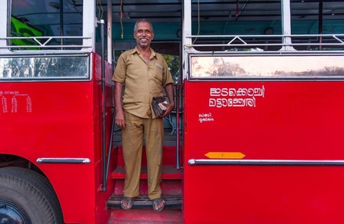 Bus driver in front of a red bus