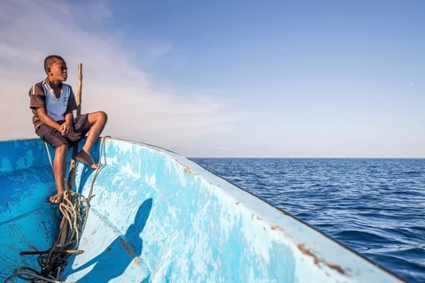 Boy on a fishing boat looking out to the sea