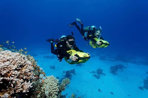 Divers with diver propulsion vehicles exploring a coral reef