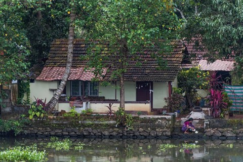 Woman washing the dishes in a canal in front of her house