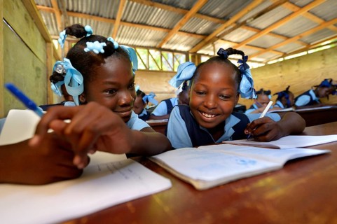 Two girls writing in a notebook