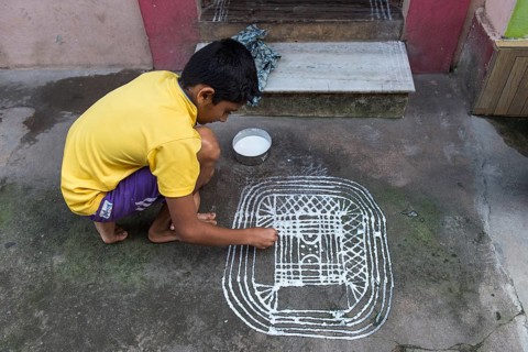 Boy painting a traditional Rangoli