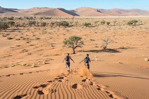 Two teens running down a dune