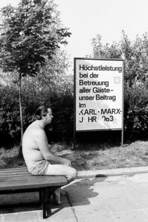 Man in swimming trunks on a bench on the shore of the Senftenberg dredging lake