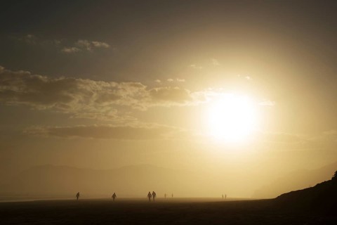People walking at the beach at sunset