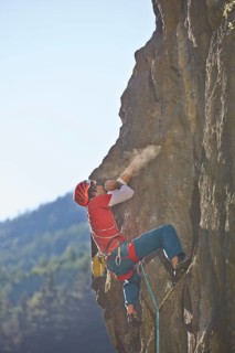 Sport climber wearing a helmet climbing a rock face