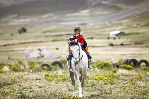 Boy from the Puruha people riding on a horse