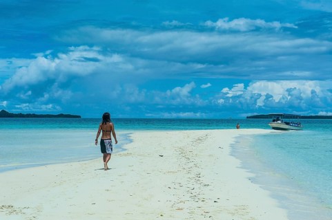 Tourist walking on a sand strip at low tide