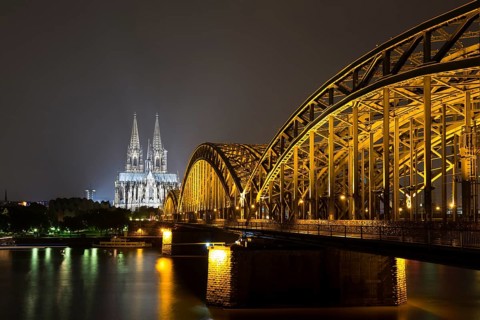 The illuminated Cologne Cathedral and Hohenzollern Bridge at night with Rhine