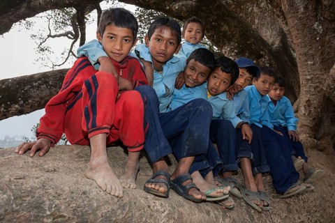 Nepalese students wearing school uniforms sitting on a tree