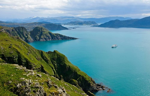 Cruise ship in a bay off the rugged cliffs of Runde island