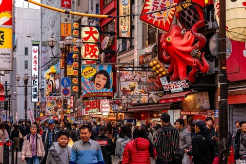 Crowd crowded in pedestrian zone with lots of illuminated advertising for restaurants and shopping centers