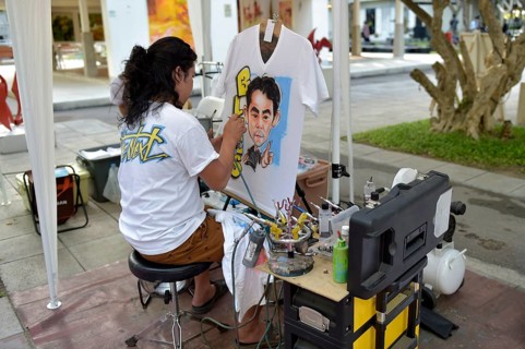 Woman airbrushing a portrait on a T-shirt