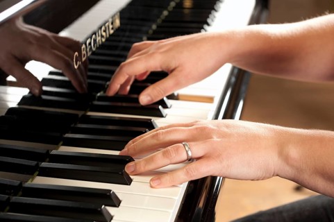 Woman's hands playing a Bechstein grand piano