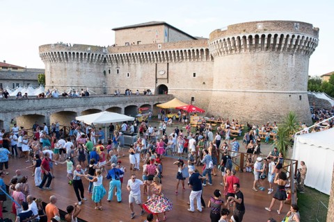 People dancing in the festival grounds in front of Fortress Rocca Roveresca