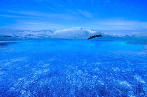 Monte Vettore at blue hour with a frozen puddle with air bubbles