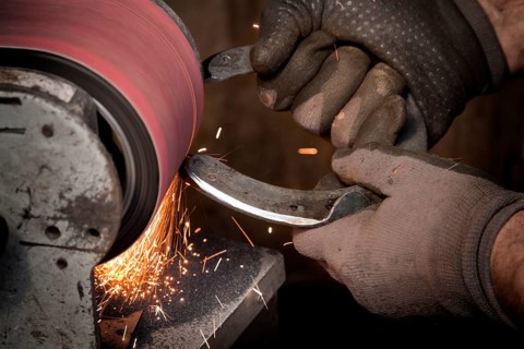 Blacksmith grinding a horseshoe