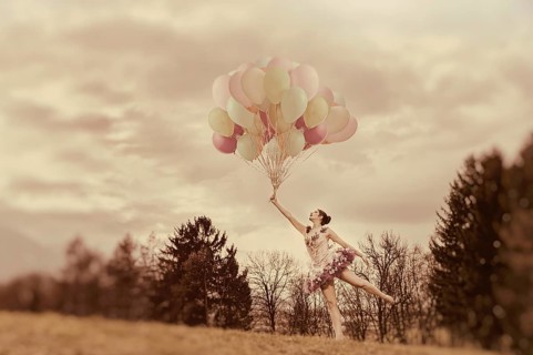 Young woman holding lots of balloons