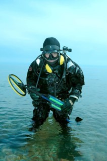 Diver with metal detector searching for underwater treasure