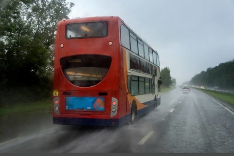 Red bus in the rain on the highway