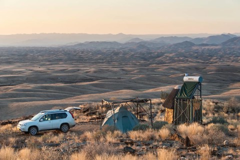 SUV next to tent and small hut