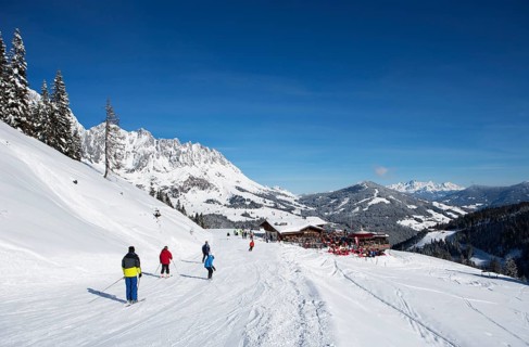 Skiers on ski slope in front of mountain scenery