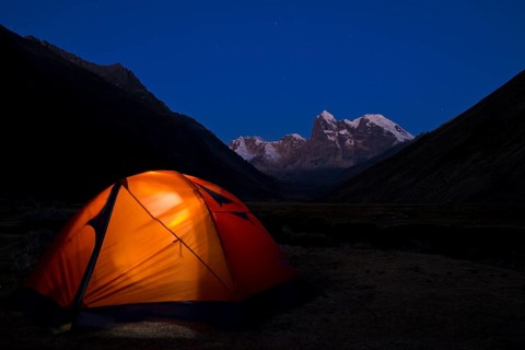 Illuminated tent at Laguna Jahuacocha lake at dusk