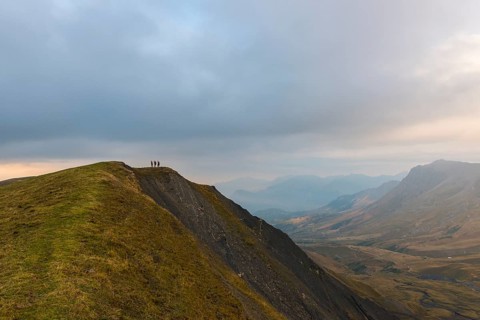 Three hikers on the ridge of a mountain in the Ecrins at dusk