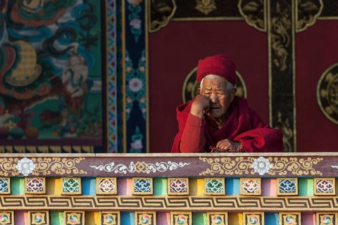 Buddhist monk on the balcony of the Cinya Llama Gompa