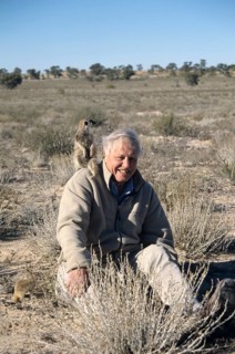 Sir David Attenborough with meerkat on shoulder for BBC series The Life of Mammals
