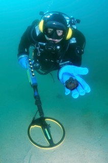 Diver with metal detector displaying found ancient coins