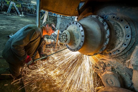 A man cutting up an armored vehicle type Marder with a torch