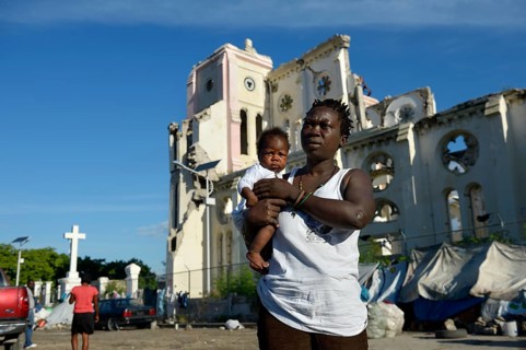 Woman holding a child in front of the ruins of the cathedral