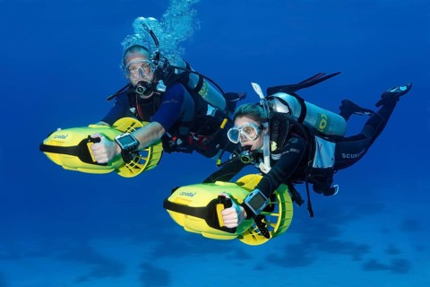 Divers with diver propulsion vehicles exploring a coral reef