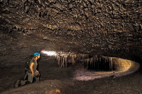 Tourist in a subterranean lava tube created by an eruption of the Piton de la Fournaise volcano