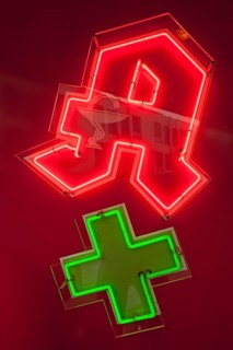 Neon sign of a pharmacy with a green cross