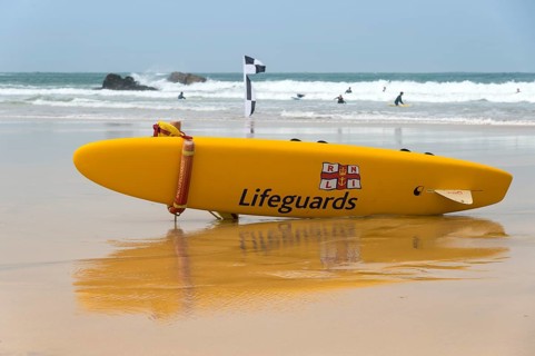 A yellow surfboard of the lifeguards is lying on the beach